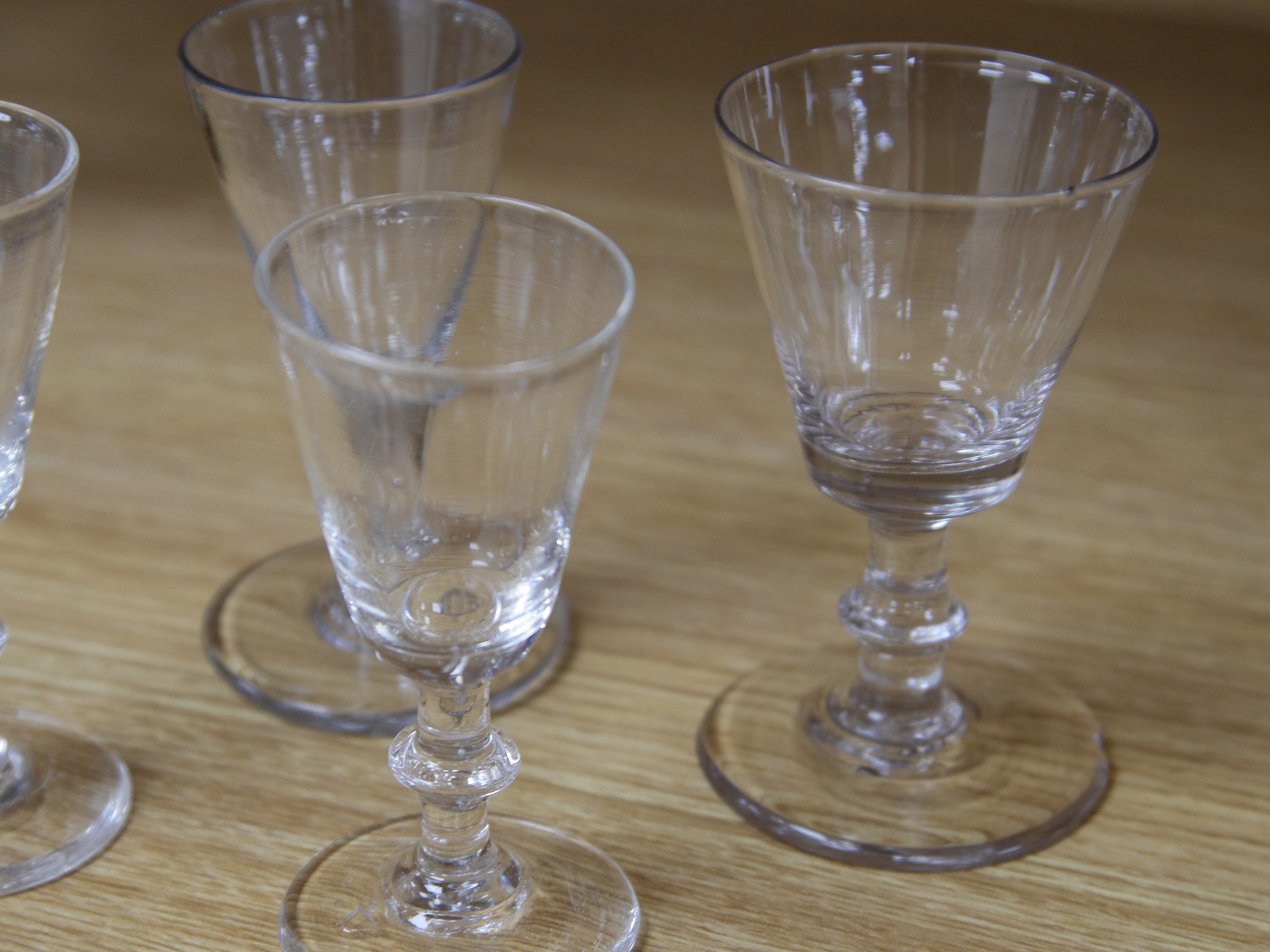 Four late 18th century ale wine and dram glasses, tallest 10.5cm. Condition - largest glass has a fine chip to rim